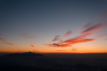 Silhouettes of mountains and low clouds at colorful sunrise in Marmarosy at winter