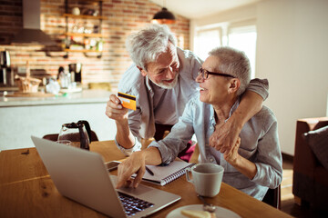 Senior couple online shopping with credit card from home