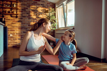 Young mother with little daughter practicing yoga at home