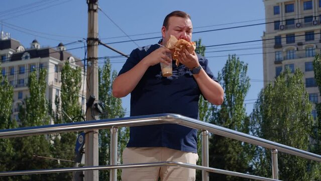 Fat guy eats fast food on the street