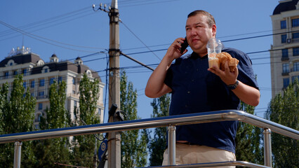 Fat guy eats fast food on the street