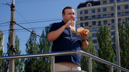 Fat guy eats fast food on the street