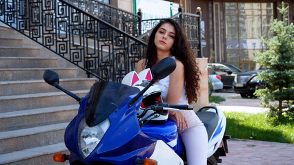Independent and beautiful girl posing on her motorcycle