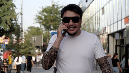 A man walks down the street and talks on the phone