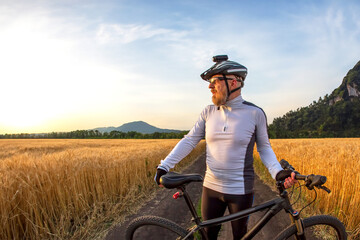 the cyclist with the bike in a field watching the sunset. sports and hobbies. outdoor activities