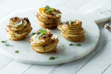 Crispy seasoned potato stacks on a marble board, garnished with parsley.