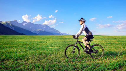 Obraz premium The cyclist rides a bicycle on the green grass on the field. Outdoor sports. Healthy lifestyle.