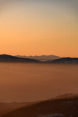 Fototapeta na wymiar Amazing vertical view of winter landscape with hills and mountains silhouettes during sunrise
