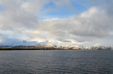 View to calm water surface of lake Sevan and snow capped mountains in distance. Picturesque landmark of Armenia
