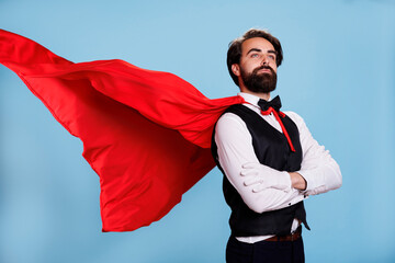 Model superhero with cartoon cape posing over blue background, wearing fantasy leader costume with...