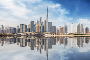 The urban skyline of Dubai Business bay with reflections of the modern skyscrapers in the water, UAE - obrazy, fototapety, plakaty