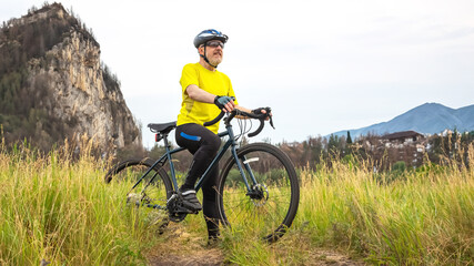 bearded man cyclist in yellow clothes is resting on a bicycle on the road in nature. sports,...