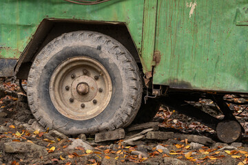 Fototapeta na wymiar A flat tire on the axle of a green car.
