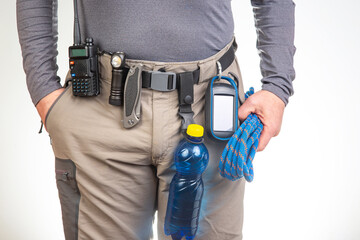 walkie-talkie, flashlight, knife, GPS navigator, climbing rope on the belt of the tourist trekking pants. equipment for tourism and travel. EDC items.