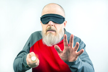 Bearded man wearing a blindfold for sleeping. Concept of a blind man searching with a flashlight in...
