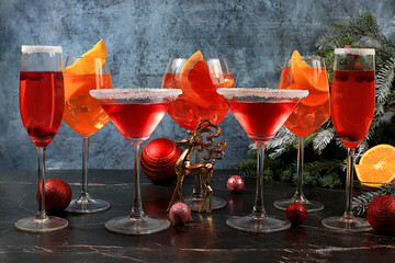 Christmas alcoholic cocktail Aperol spritz, red Martini, pink champagne on holiday background with fir branches and decorations, bar concept and New Year's Eve, alcoholic drinks at party,