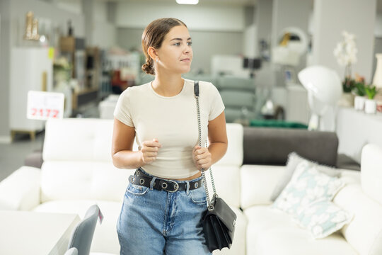 Positive female shopper choosing new upholstered furniture in a furniture store