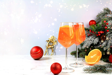 Christmas alcoholic cocktail Aperol spritz in glasses on festive background with fir branches and...
