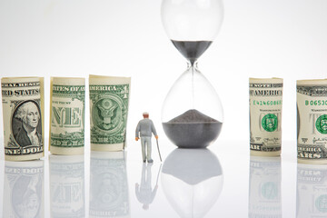 Miniature people. an elderly pensioner man stands near dollar money, an hourglass. concept of time...