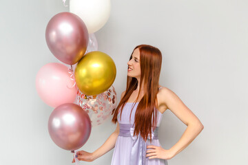 Fototapeta na wymiar Happy young millennial attractive redhead woman hold balloons smiling celebrating her birthday at home holiday surprise party.Womens,Valentines,Mother day