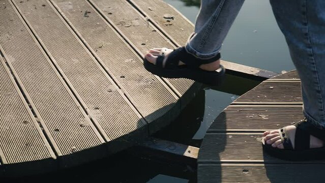 A woman walks on round blocks that float on the surface of a pond in the park