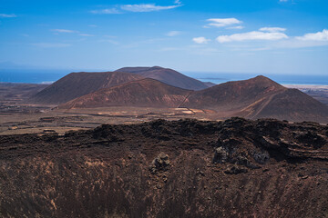 View of a part of the crater of one of the most famous volcanoes on the island and in the background the sea with several more volcanoes. Photography taken in Fuerteventura, Canary Islands, Spain.