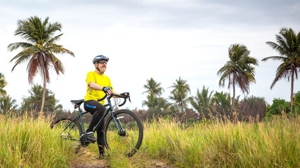 bearded male cyclist in yellow clothes on a bicycle against the background of palm trees in nature. sports, hobbies and entertainment for health