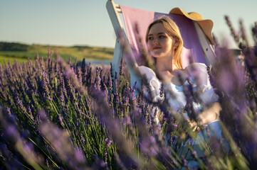 Relaxed young girl in a white dress, sitting in a chair, breathing fresh air, sitting in a lavender field on a sunny day, looking to the side, thinking