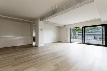 Large empty modern living room of a residential home with light wooden floors, exposed concrete...
