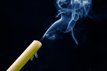 Smoke from an extinguished candle on a dark background. The concept of spirituality and the end of...
