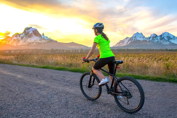 Fototapeta premium Beautiful woman cyclist rides a bicycle on a road. Healthy lifestyle and sports. Leisure and hobbies