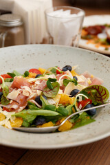 Salad with prosciutto, parmesan, berries in a restaurant, close-up. Healthy eating.
