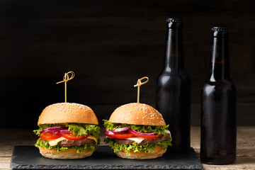 Two hamburgers, french fries, bottled beer on a wooden background. Fast food, pub food, homemade burgers