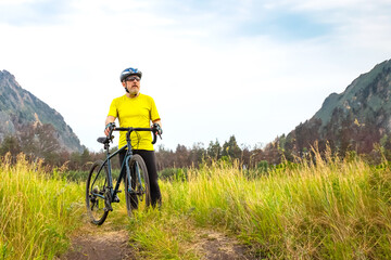 Fototapeta premium bearded man cyclist in yellow clothes rides a bike on a road in nature. sports, hobbies and entertainment for health