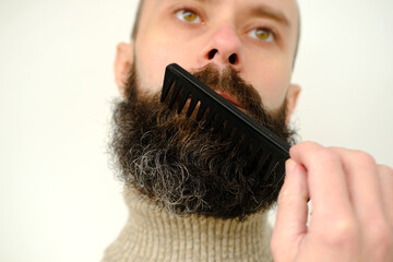 close-up of male face, young bearded and mustachioed man, guy with 25 - 30 years combs his thick...