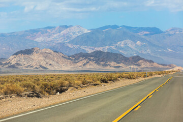 View of Mojave Desert national reserve landscape, an arid rain-shadow desert, California, United States of America, summer sunny day with road, mountains, sand dunes and a blue sky