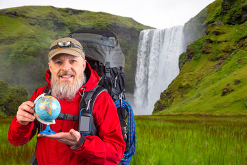 bearded tourist in a red jacket holds a model of the world globe in his hands. tourism and travel...