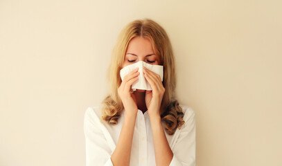Sick exhausted caucasian young woman employee sneezing blow nose using tissue at home - obrazy, fototapety, plakaty