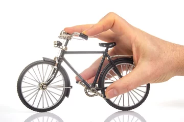 Fotobehang man hand on a bicycle model on a white background. cycling concept © photosaint