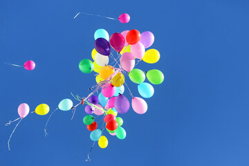 many multicolored balloons flying in the blue sky. Holiday accessories and decorations