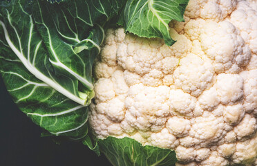Fresh organic white cauliflower cabbage with leaves on old rustic green table background, top view