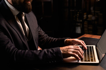 Close up of businessman using his laptop. Man wear luxury suit working at home office. Confident...
