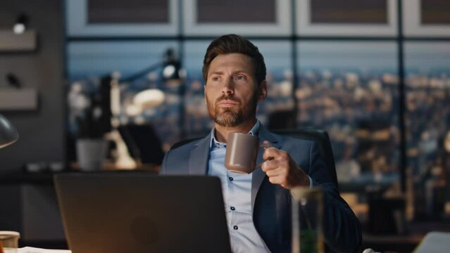 Pensive businessman drinking tea in night office closeup. Director taking break