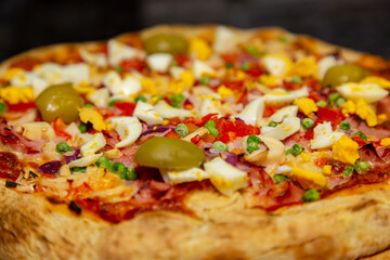 Traditional Portuguese pizza with ham, eggs, peppers, hearts of palm, tomatoes, onions, peas and cheese