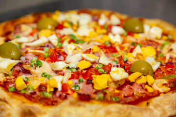 Traditional Portuguese pizza with ham, eggs, peppers, hearts of palm, tomatoes, onions, peas and...