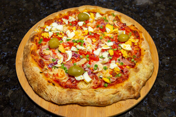 Traditional Portuguese pizza with ham, eggs, peppers, hearts of palm, tomatoes, onions, peas and cheese