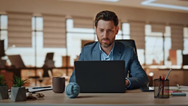 Positive boss putting cellphone working at modern agency. Manager looking laptop