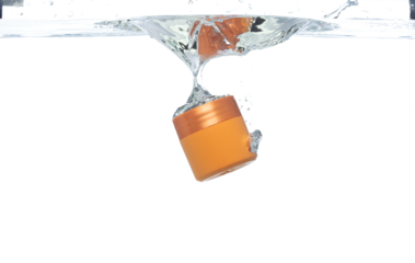 Orange Cosmetic container fall into clear water with air bubble. Cosmetic treatment container drop to clear water of freshness. White background isolated freeze element