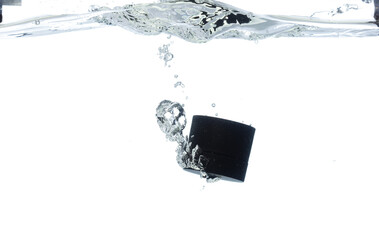 Black Cosmetic container fall into clear water with air bubble. Cosmetic treatment container drop...