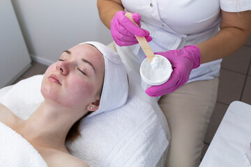 Cropped Cosmetologist, Beautician Applying Moisturizing Mask, Cream On Woman's Red Skin After Chemical Peeling In Beauty Salon. Cosmetology And Face Skin Care. Facial Treatment. Horizontal Plane